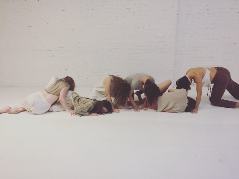 A group of artists in a long tableau arrange themselves on the floor.